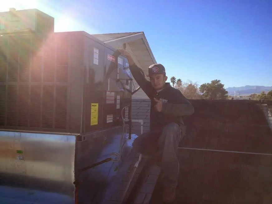 HVAC technician performing Heat Pump Repair on a rooftop unit in Norman